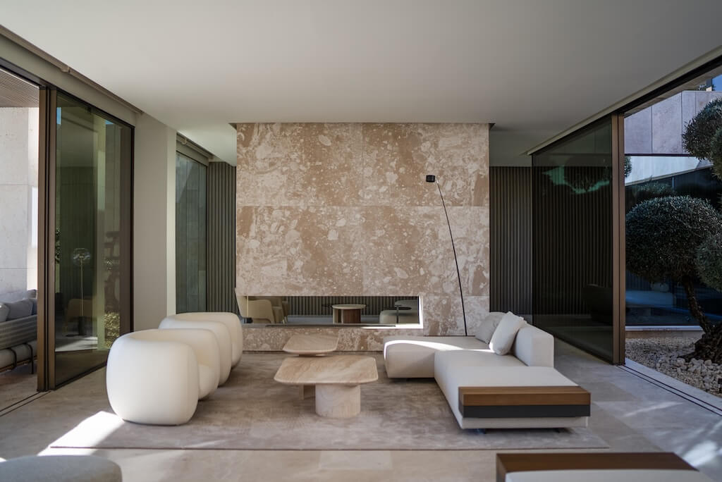 Airy contemporary interior with pale stone, sculptural furniture and garden views